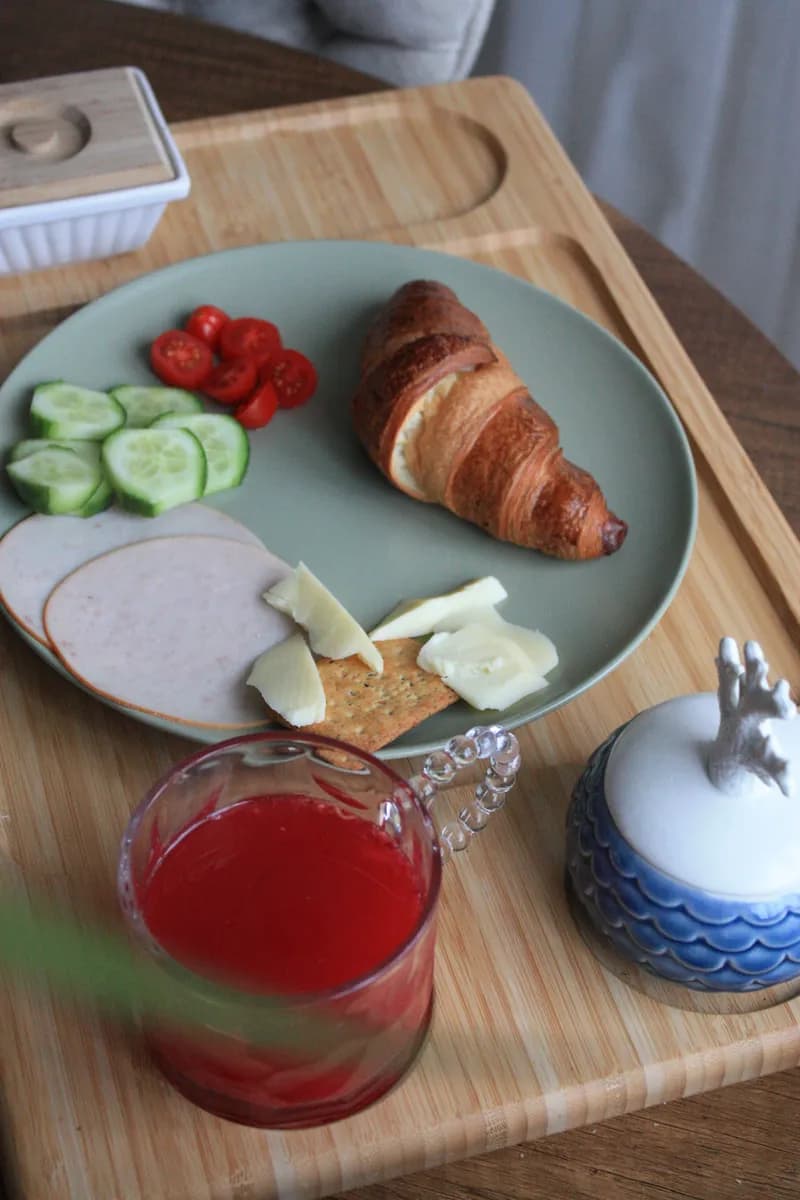 BookNoFees-esimerkkikuva: Aamiaistarjotin, jossa on croissant, vihanneksia ja mehua