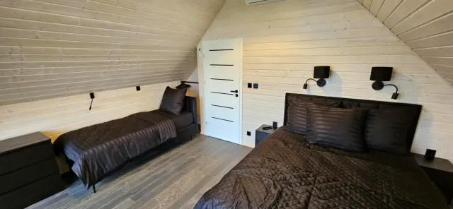 BookNoFees: semesterboende i Rusinowo, Polen – ett sovrum med en säng och två vägglampor i anläggningen Black Barn i staden Rusinowo