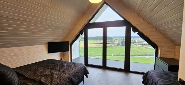 BookNoFees: semesterboende i Rusinowo, Polen – ett sovrum med ett stort fönster i ett hus i bostadsområdet Black Barn i staden Rusinowo