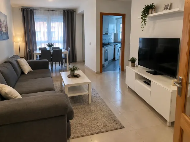 BookNoFees: semesterboende i Madrid – Vardagsrum med grå soffa, vitt soffbord och platt-TV på ett vitt skåp, med matplats och kök i sikte
