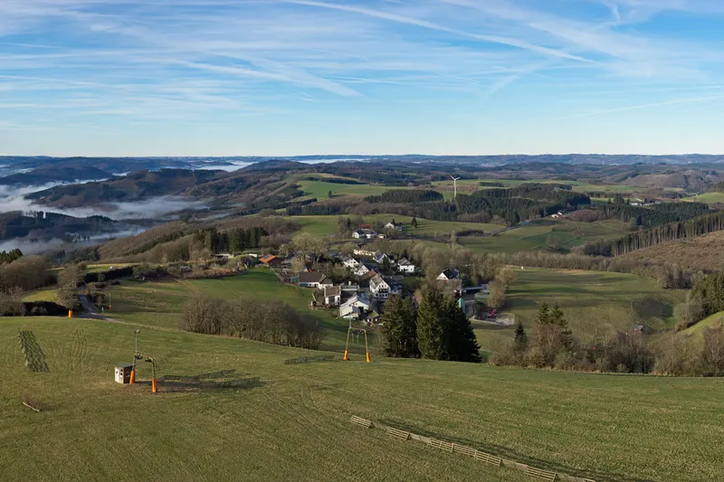 Wildewiese Sauerlandin kukkuloilla: niityllä on hiihtohissi ja sen alapuolella sijaitsee kylä