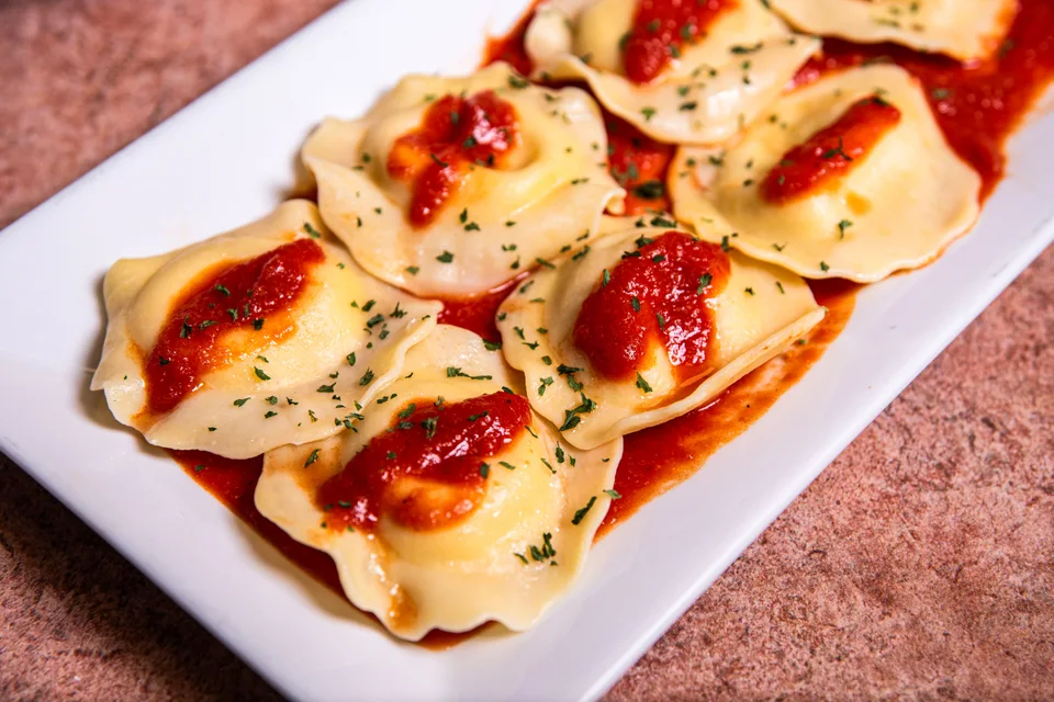 Exempelbild: Ravioli toppad med tomatsås och örter på en vit tallrik