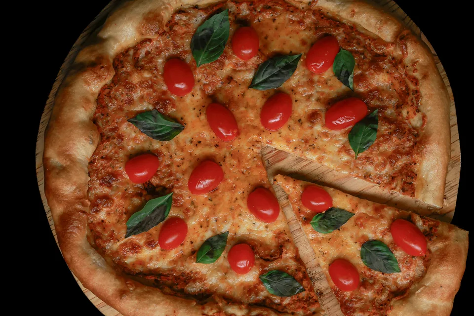 BookNoFees: Esimerkkikuva: Pizza, jonka päällä on tomaatteja ja basilikaa